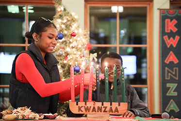 A student lights candles on the Kinara. Links to Gifts of Appreciated Securities