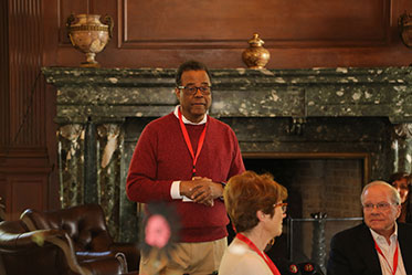 A man patiently waits for any questions from the people sitting at an event.