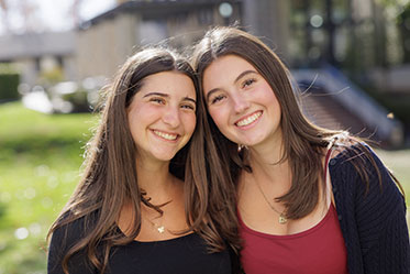 Two students smile together. Links to Gifts of Life Insurance